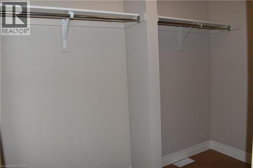 Spacious walk-in closet featuring dual clothing rods with metal brackets, white painted walls, and wood-finish flooring - 8 Dunlop Road, Hamilton, ON - Indoor Photo Showing Other Room