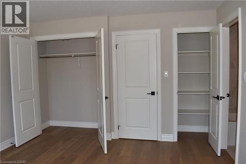 Generous bedroom featuring multiple built-in closets with shelving and hanging rods, wood-finish flooring, and abundant natural light from dual windows - 8 Dunlop Road, Hamilton, ON - Indoor Photo Showing Other Room
