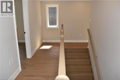 Elegant staircase with natural wood-finish treads and a coordinating handrail, bathed in natural light from an upper window - 8 Dunlop Road, Hamilton, ON - Indoor Photo Showing Other Room