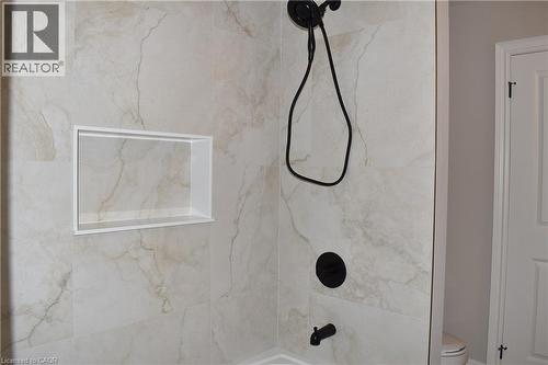 Shower enclosure featuring large format stone-finish wall tile, built-in recessed niche, and matte black shower fixtures with a handheld spray - 8 Dunlop Road, Hamilton, ON - Indoor Photo Showing Bathroom
