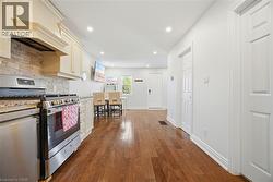 Modern kitchen featuring stainless steel appliances, light-toned cabinetry, a stone backsplash, and granite-style countertops - 