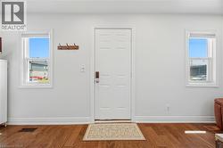 Entryway with a paneled white door, wood-finish flooring, and two double-hung windows - 