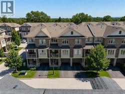 Brick and stone exterior townhome featuring multiple balconies, bay windows, and attached garages - 