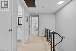 Upper-level hallway featuring neutral wall paint, recessed lighting, and a dark wrought iron railing - 