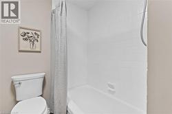 Bathtub and shower combination featuring white tiled surround and a handheld shower fixture - 
