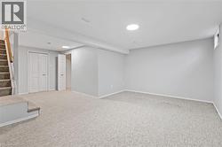 Finished lower level featuring light gray walls, neutral carpeting, recessed lighting, and a window for natural light - 