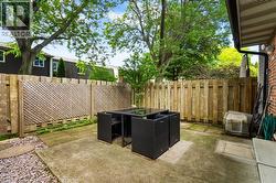 Private rear patio featuring concrete surfacing, a full-height wooden privacy fence, and lattice panel accents - 