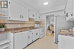 Kitchen featuring white cabinetry with black hardware, mottled countertops, and a tiled backsplash - 
