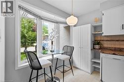 Kitchenette featuring a large bay window, pendant lighting, white cabinetry, a built-in pantry, and a tiled backsplash - 