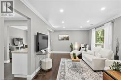 Spacious living area featuring dark wood-finish flooring, recessed lighting, and crown molding - 