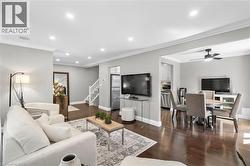Expansive living area with recessed lighting, crown molding, dark wood-finish flooring, and a staircase with white risers - 