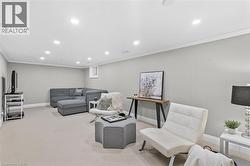 Recessed lighting illuminates this versatile space featuring light-colored carpeting, a neutral wall palette, crown molding, and a visible window - 