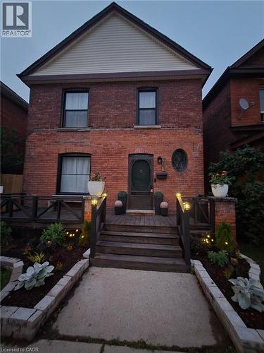 Brick facade residence featuring a front entry deck with wood railings and steps - 361 Cumberland Avenue, Hamilton, ON 