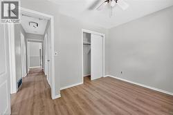 Bedroom featuring wood-finish flooring, light gray walls, and white trim - 