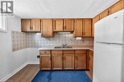 Functional kitchen space featuring wood cabinetry, a double basin sink, and a light-colored countertop - 