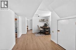 Hallway featuring wood-finish flooring, white walls, and white trim - 