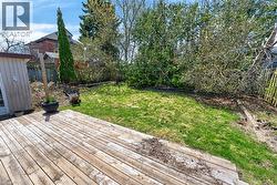 Expansive backyard featuring a wood deck, green lawn, and mature perimeter trees - 
