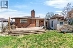 Expansive grassy backyard featuring a multi-level wood deck, a brick exterior, a window, and a separate storage shed - 