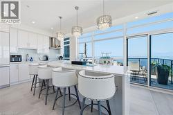 Modern kitchen featuring white cabinetry, a large center island with seating, a stainless steel range hood, and tile flooring - 