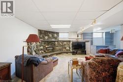 Spacious room featuring a stone fireplace with a raised hearth, built-in shelving, and recessed ceiling lighting - 