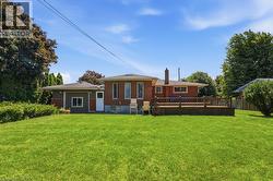 Expansive green lawn surrounds the rear of the property, featuring a brick exterior with a wood deck - 