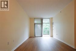 Spacious living area featuring wood-finish flooring, a sliding glass door with vertical blinds, and balcony access - 