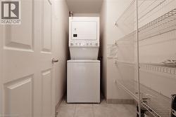 Dedicated laundry area featuring a white stackable washer and dryer unit, complemented by white wire shelving for organized storage - 