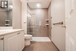 Bathroom featuring a walk-in shower with glass enclosure, rain showerhead, and grab bars - 