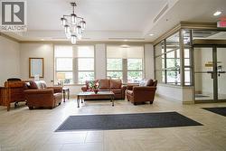 Spacious reception area featuring light-toned tile flooring, large windows with roller shades, and a multi-light chandelier - 