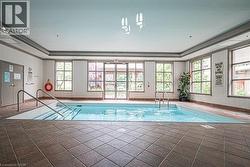 Indoor swimming pool featuring a tiled surround, multiple windows, and direct access to an exterior area - 