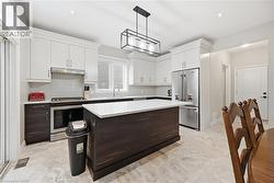 Modern kitchen featuring white upper cabinetry, dark wood-finish lower cabinetry, and a central island with a white countertop - 