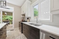 Contemporary kitchen featuring two-tone cabinetry, stainless steel appliances, a double basin sink, and white countertops - 