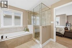 Bathroom featuring a built-in tub with tile surround, a glass-enclosed shower, and neutral wall paint - 