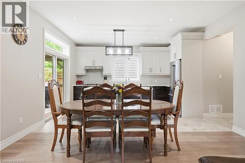 Open-concept dining area featuring wood-finish flooring, a modern linear chandelier, and a sliding glass door - 1 Lindsay Way, Grimsby, ON - Indoor Photo Showing Dining Room