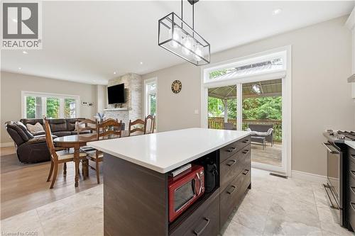 Open-concept interior featuring a central kitchen island with a light-toned countertop, a built-in cooktop, and a sliding glass door leading to an exterior deck - 1 Lindsay Way, Grimsby, ON - Indoor