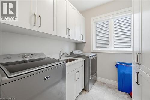 Laundry room featuring white shaker cabinetry, an integrated utility sink, white countertops, and light gray tiled flooring - 1 Lindsay Way, Grimsby, ON - Indoor Photo Showing Laundry Room