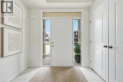Entryway featuring a white paneled door with sidelights and transom window, light-toned tile flooring, and integrated recessed lighting - 