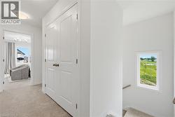 Hallway featuring neutral carpet, white paneled doors with bronze hardware, and a semi-flush mount ceiling light - 