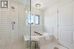 Contemporary bathroom featuring a spacious walk-in shower with a glass enclosure, white rectangular tile walls, and a built-in shower bench - 