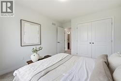 Bedroom featuring light gray wall paint, carpet flooring, and a double-door closet with panel detailing - 