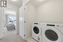 Dedicated laundry area featuring front-loading appliances, white walls, and light-toned flooring - 