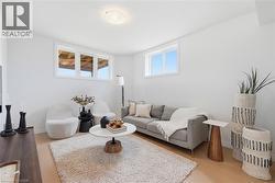 Living area featuring light wood-finish flooring, white walls, and recessed windows - 