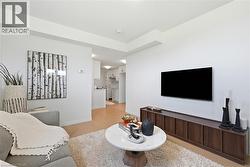 Open-concept living space featuring light-toned flooring, a wall-mounted television, and a wood-finish media console - 