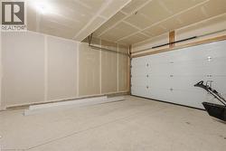 Garage space featuring an overhead door, exposed ceiling joists, and unfinished drywall walls - 
