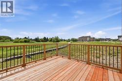 Wood-decked outdoor living space featuring a natural wood railing with black balusters - 