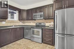 Kitchen featuring dark wood cabinetry and stainless steel appliances - 