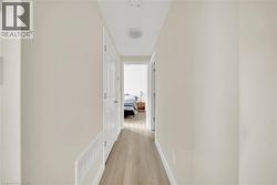 Hallway featuring wood-finish flooring, light-toned wall paint, white trim, and a ceiling-mounted light fixture - 