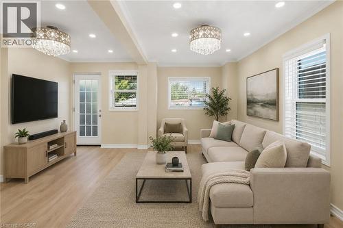 Virtually Staged - Spacious living area featuring light wood-finish flooring, recessed lighting, and crown molding - 309 Cope Street, Hamilton, ON - Indoor Photo Showing Living Room