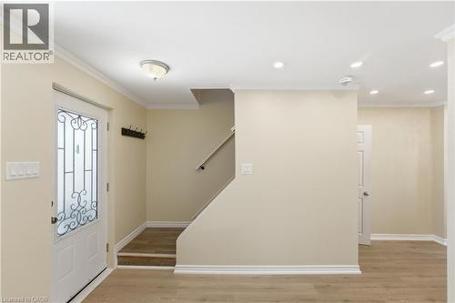 Entryway featuring a white door with decorative ironwork, wood-finish flooring, staircase with wood-finish treads, overhead flush mount light, and recessed lighting - 309 Cope Street, Hamilton, ON - Indoor Photo Showing Other Room