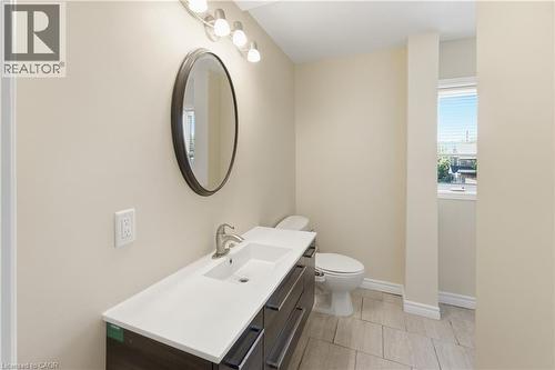 Bathroom featuring a white integrated sink with a brushed nickel faucet, a dark wood-finish vanity with drawer storage, and a large oval mirror - 309 Cope Street, Hamilton, ON - Indoor Photo Showing Bathroom